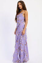 Side view of lavender floral ruffle maxi dress with cowl neckline, spaghetti straps, cascading ruffles and front slit.
