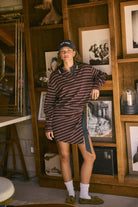 Model wearing burgundy Varsity Club Striped Polo Mini Dress with navy collar, wrap-style skirt and side tie in a vintage-inspired interior.