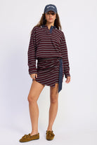 Full-length front view of burgundy striped polo mini dress styled with navy baseball cap and brown loafers.