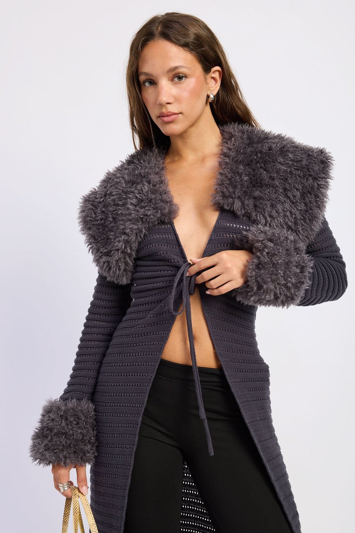 Woman wearing grey tie-front cardigan, close view of plush collar and cuffs against white background.