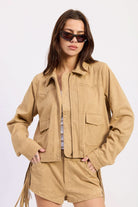 Woman wearing cropped suede-look jacket with collar and long sleeves in Latte against white background.