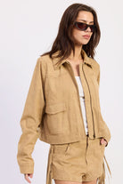Woman wearing cropped suede-look jacket with collar and long sleeves in Latte.