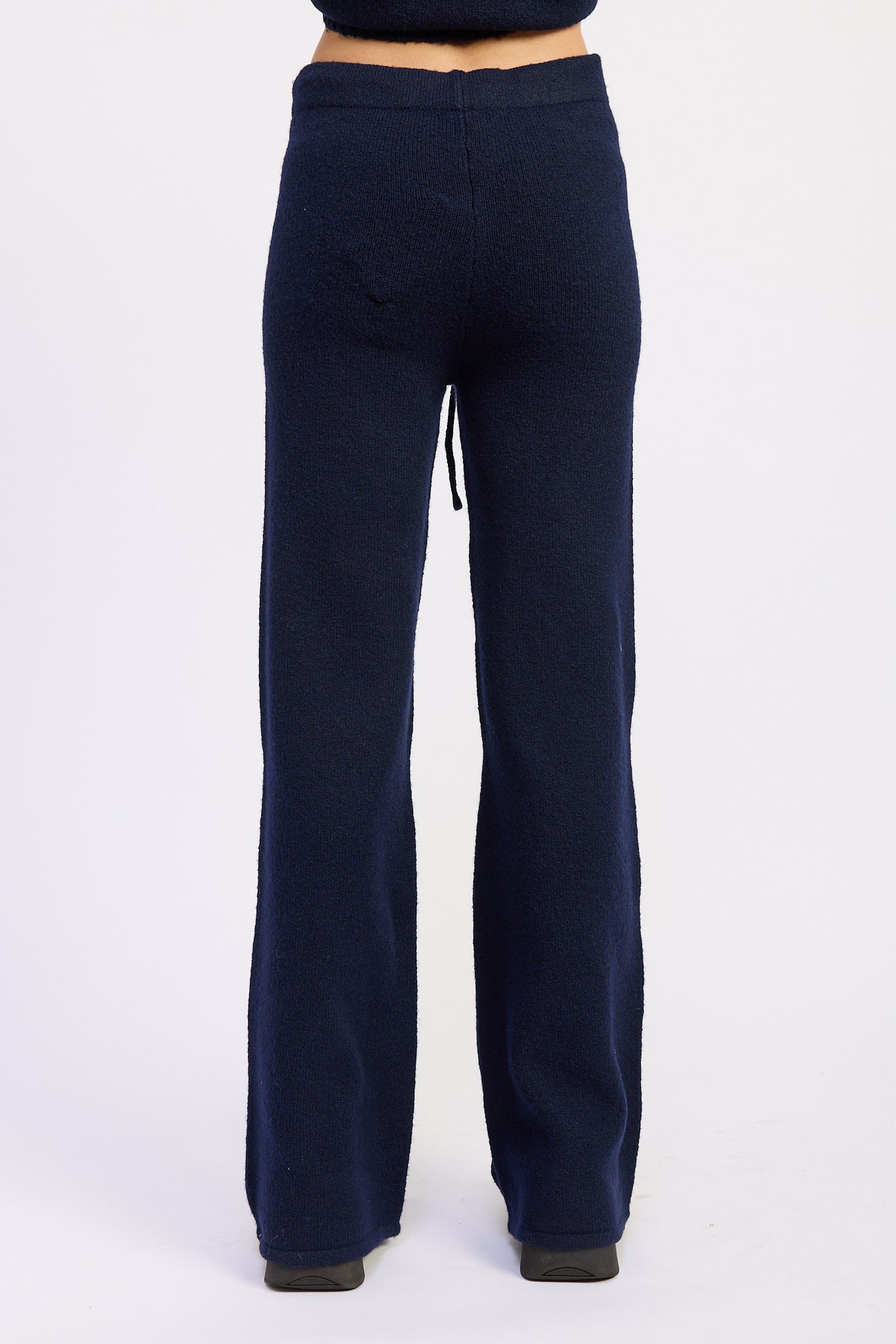 Back view of navy wide leg knit pants showing smooth waistband and straight leg shape.