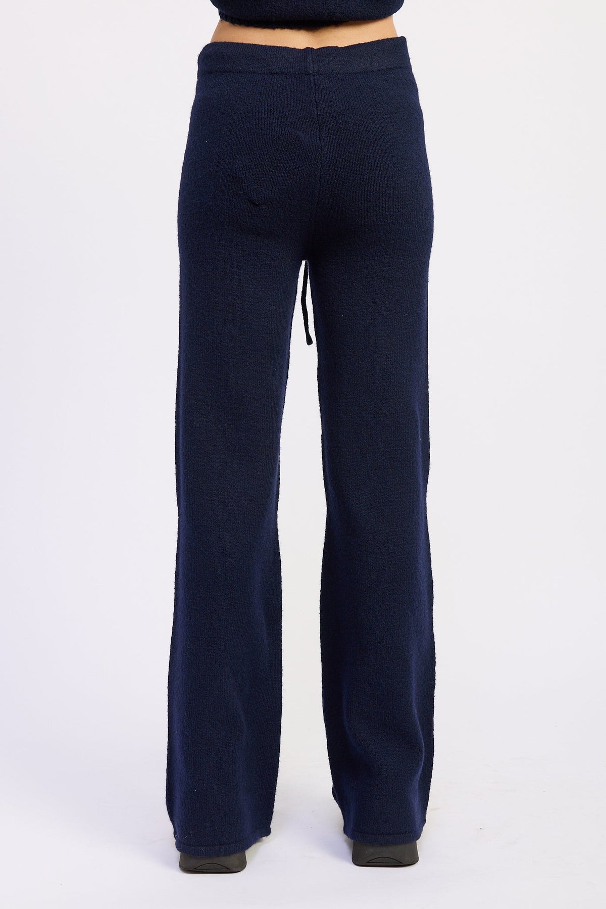 Back view of navy wide leg knit pants showing smooth waistband and straight leg shape.