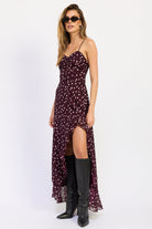 Woman wearing polka dot maxi dress with spaghetti straps and ruffled asymmetric hem in Wine.
