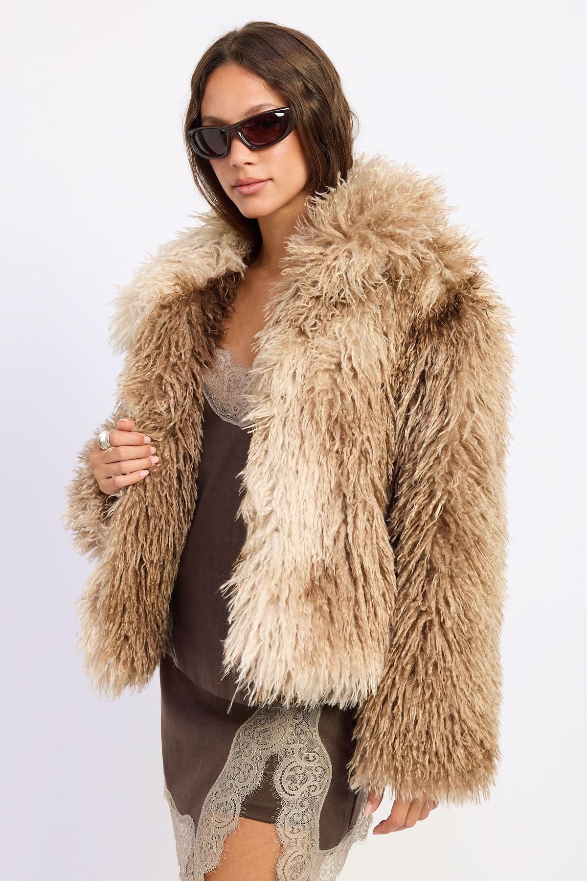Woman wearing brown tie-dye oversized shaggy faux fur coat.