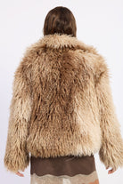 Woman wearing brown tie-dye oversized shaggy faux fur coat.