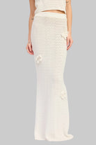 Woman wearing an ivory crochet top and ivory crochet maxi skirt with floral applique details set on a white background