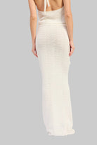 Woman wearing an ivory crochet top and ivory crochet maxi skirt with floral applique details set on a white background back view