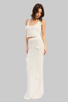 Woman wearing an ivory crochet top and ivory crochet maxi skirt with floral applique details set on a white background