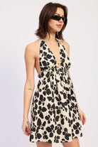 Woman wearing a black floral halter mini dress front view flowy silhouette on a plain background