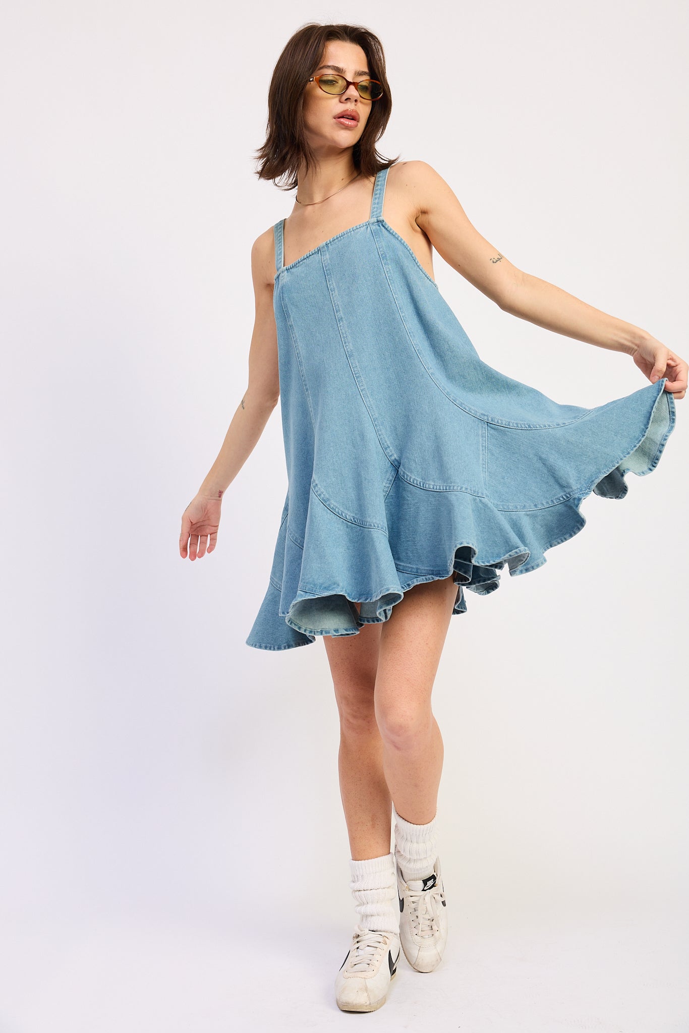 Woman wearing a light blue denim dress against a white background, front view