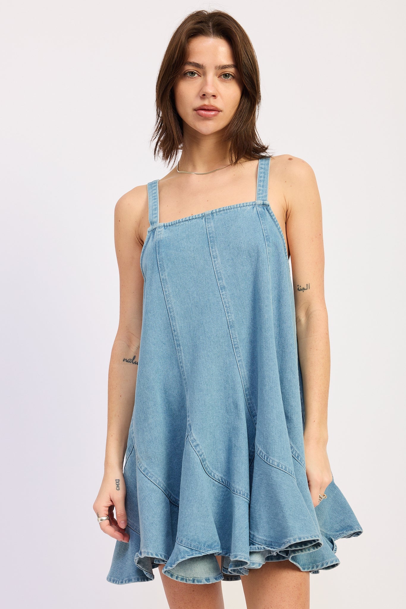 Woman wearing a light blue denim dress against a white background, front view