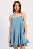 Woman wearing a light blue denim dress against a white background, front view