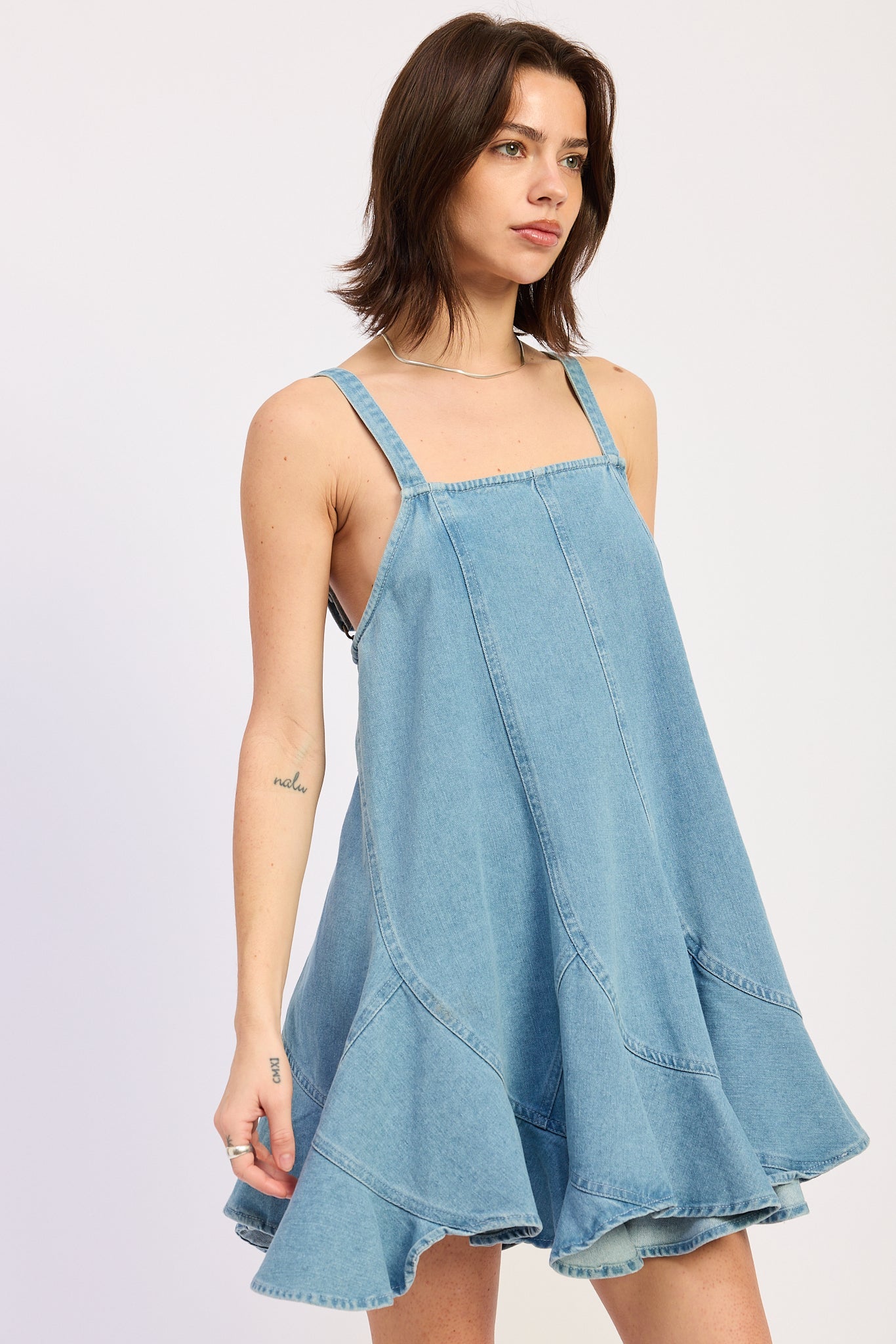 Woman wearing a light blue denim dress against a white background, front view