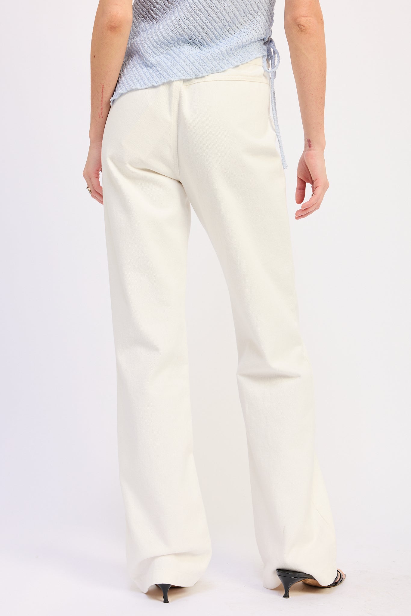 Woman wearing Buckle Wide Leg cream color cotton Pants on a white background back view