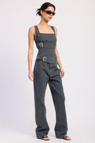 Woman wearing a washed charcoal denim corset top with buckle detail front view with sunglasses on a plain background front angle view