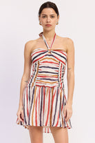 Woman wearing a striped halter mini dress front view with multicolor vertical stripes on a white background