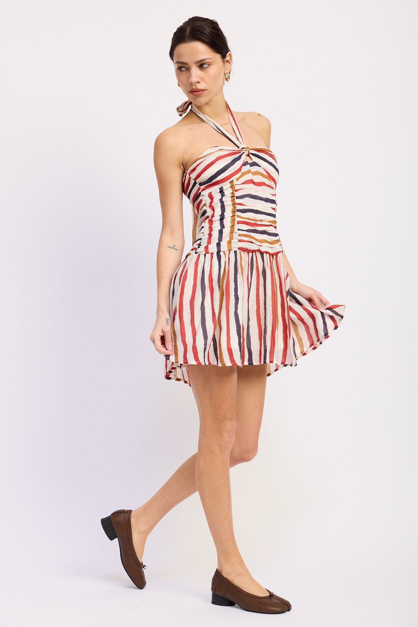 Woman wearing a striped halter mini dress front view with multicolor vertical stripes on a white background front angle view
