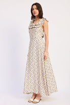 Woman wearing an Ivory floral ruffle maxi dress front view with blue floral print on a white background front angle view