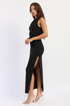Black one shoulder maxi dress with high side slit and draped neckline, side view.