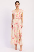 Woman wearing an ivory and pink floral ruffle maxi dress with V neckline, flutter sleeves, waist cutouts and front slit
