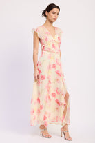 Side view of ivory and pink floral ruffle maxi dress with V neckline, flutter sleeves, waist cutouts and front slit
