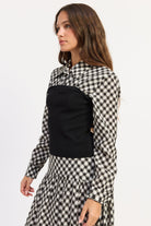 Side view of Thea black plaid collared top showing long sleeves and fitted contrast knit panel.