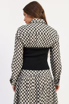 Back view of Thea black and ivory plaid top showing collared shirt detail and fitted black knit body.