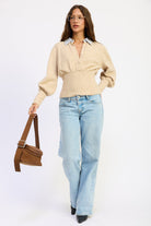 Full length model wearing oatmeal Cambridge Contrast Collar Sweater with striped collar, fitted waist and light wash jeans.