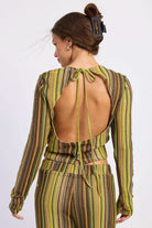 Woman wearing green and brown crochet top, back view showing open back and neck tie against white background.