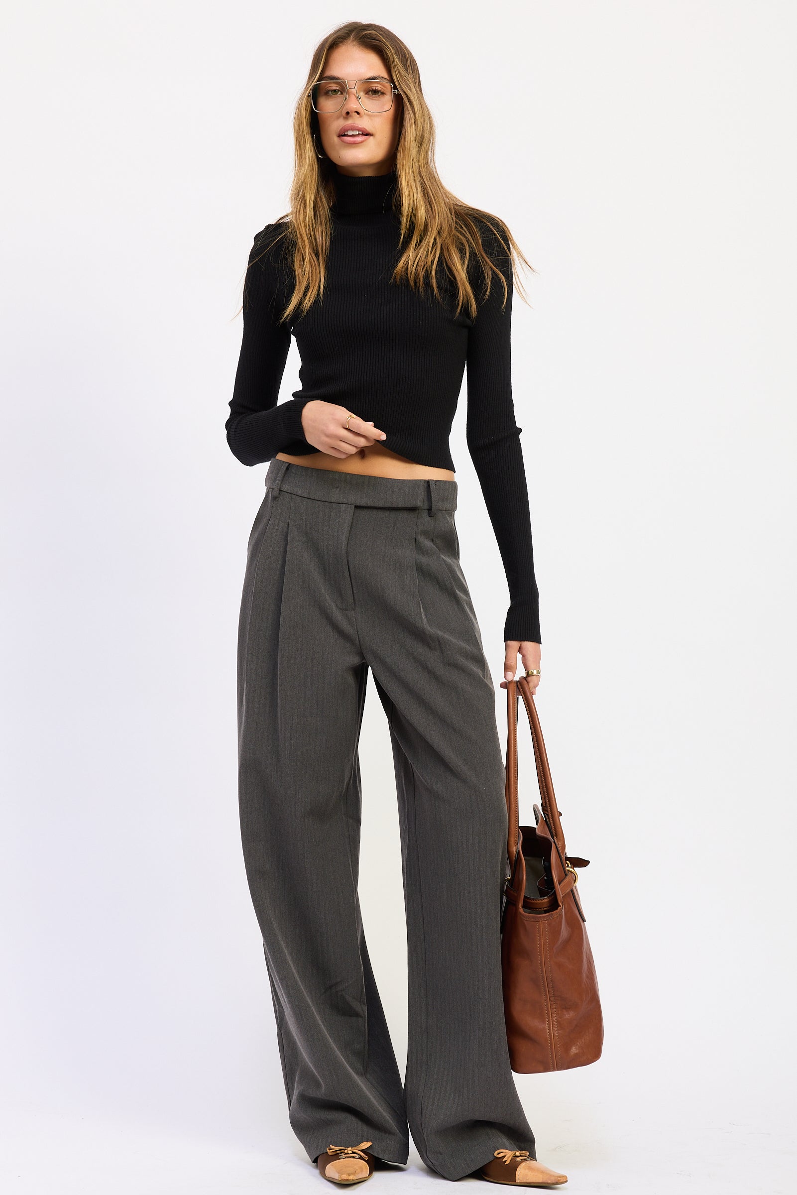 Model styling charcoal gray Madison Wide Leg Trousers with a black cropped knit top, brown tote and pointed toe flats.