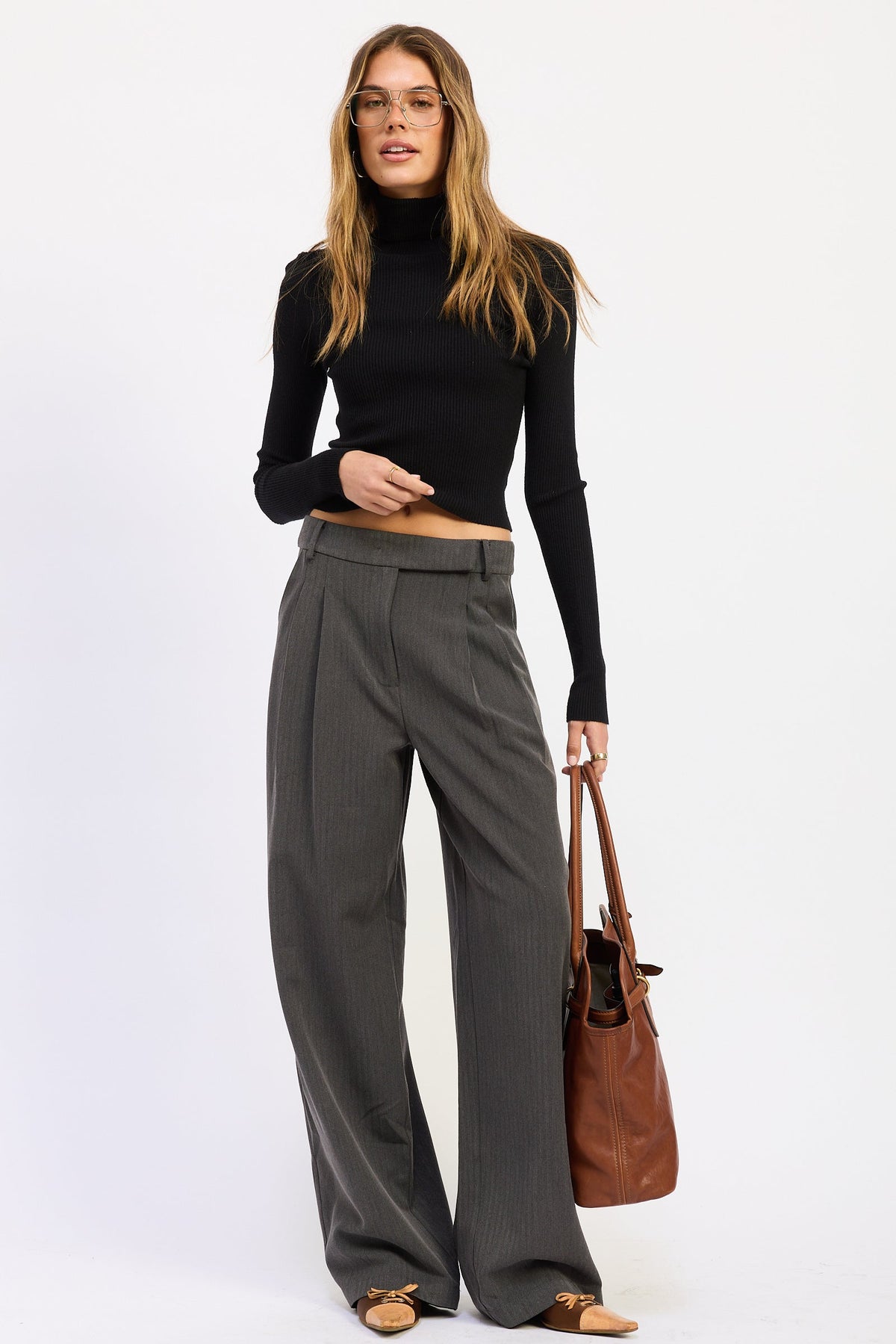 Model styling charcoal gray Madison Wide Leg Trousers with a black cropped knit top, brown tote and pointed toe flats.