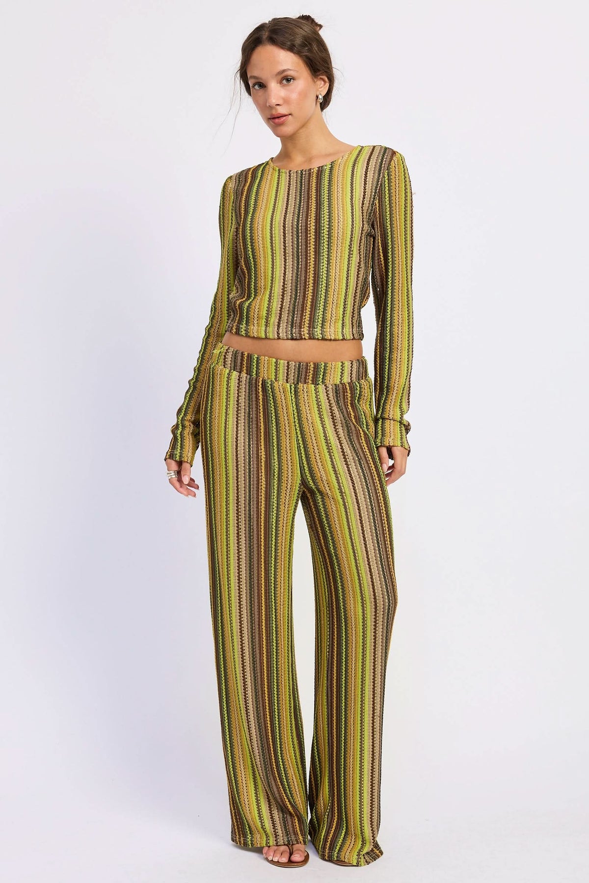 Woman wearing green and brown striped crochet wide-leg pants with matching cropped top against white background.
