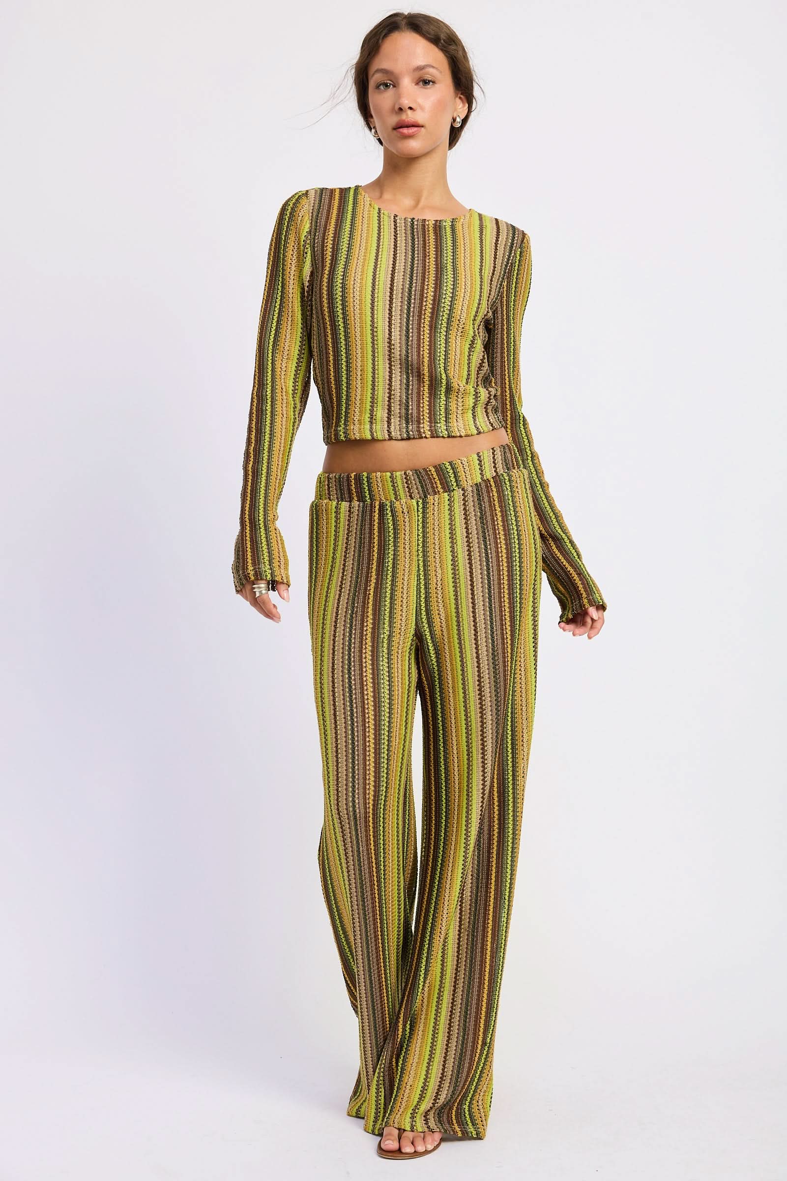 Woman wearing green and brown crochet wide-leg pants with matching long-sleeve top against white background.