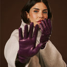 Woman wearing purple leather gloves against a brown background