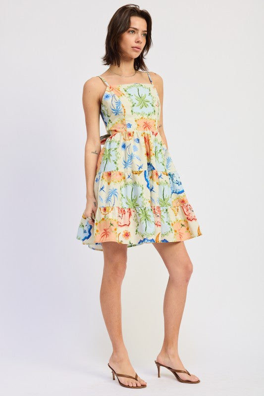 Woman wearing a scarf-inspired print blend of palm motifs and delicate detailing for a vibrant colorful floral tiered mini dress with spaghetti straps on a white background front angle view