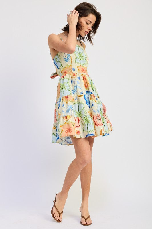 Woman wearing a scarf-inspired print blend of palm motifs and delicate detailing for a vibrant colorful floral tiered mini dress with spaghetti straps on a white background back view