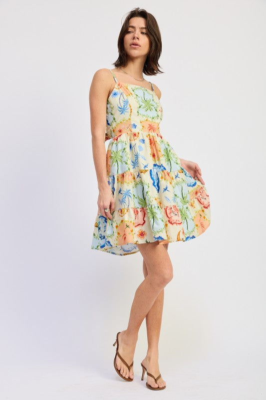 Woman wearing a scarf-inspired print blend of palm motifs and delicate detailing for a vibrant colorful floral tiered mini dress with spaghetti straps on a white background front angle view