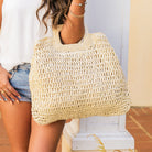 100% natural straw tote with wooden handles, top zipper closure, and a small sidewall pocket in cream