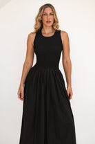 Woman wearing a black sleeveless dress against a white background