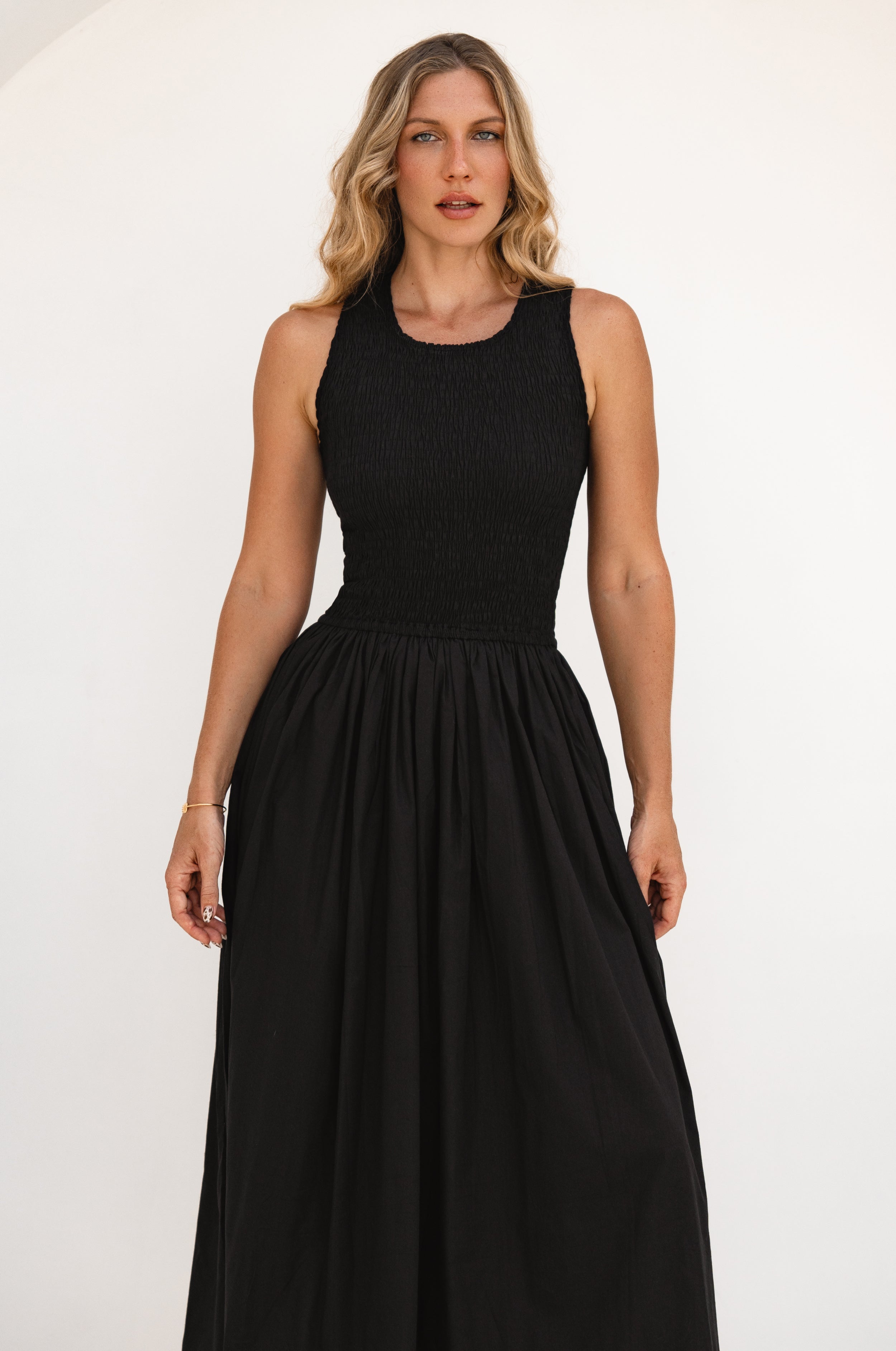 Woman wearing a black sleeveless dress against a white background