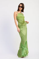 Woman wearing a green orchid print open back cami top with slim straps sleeveless top with a white background front angle view