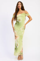 Woman wearing a soft green floral off shoulder maxi dress with ruched sleeves and fitted silhouette
