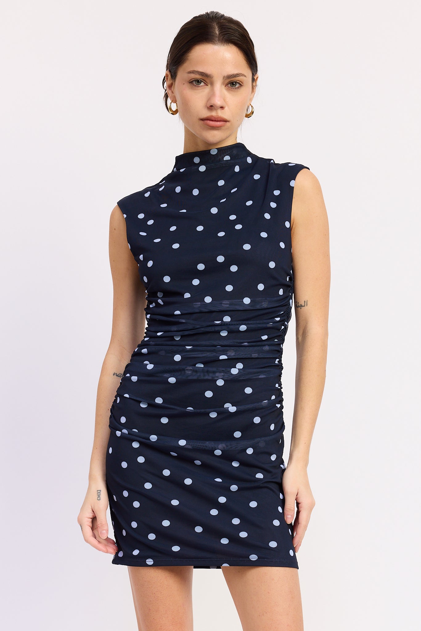Woman wearing a navy Navy mini with white polka dots ruched dress front view