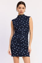 Woman wearing a navy Navy mini with white polka dots ruched dress front view
