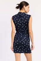Woman wearing a navy Navy mini with white polka dots ruched dress back view