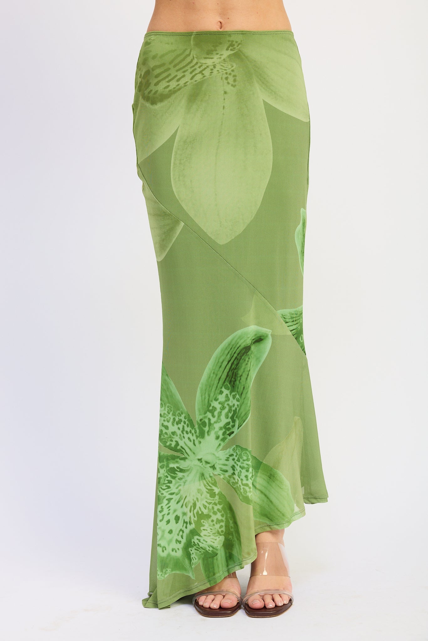 Woman wearing a green orchid print floral maxi skirt and matching open back cami top with slim straps sleeveless top with a white background front view