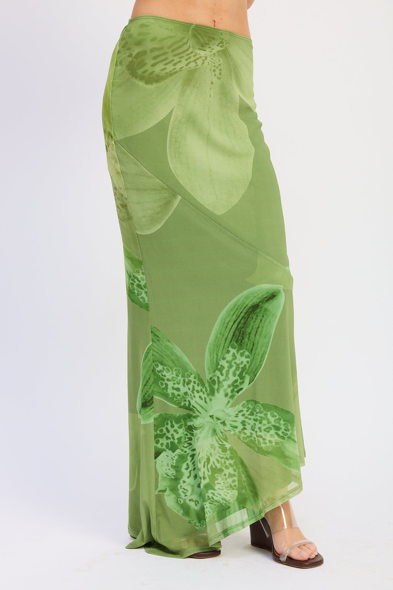 Woman wearing a green orchid print floral maxi skirt and matching open back cami top with slim straps sleeveless top with a white background front view