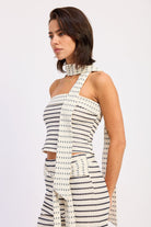 Woman wearing an ivory striped bandeau top with a scarf on a white 